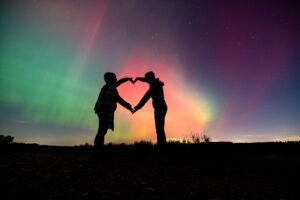 Couple silhouetted against a colorful night sky